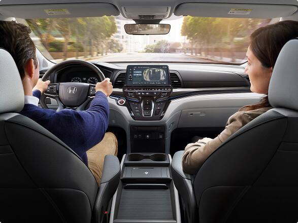 Tablero, volante y frente de la cabina de la furgoneta familiar Honda Odyssey Elite 2027 con pasajeros (minivan).